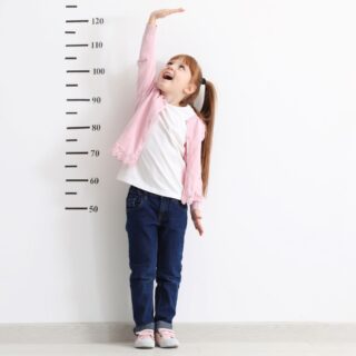 dziewczynka sprawdza swój wzrost stojąc przy ścianie